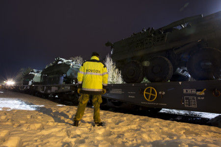 A Norwegian soldier from the Home Guard supervises the loading process of several Light Armored Vheicles and other heavy equipment in Rena, Norway.  One of several transportation options for moving U.S. Marine Corps fighting vehicles and equipment is by train. Rena, Norway was the location where Light Armored Vehicles were loaded after training with the Telemark Battalion.  The crews are now trained and the vehicles have been tested in harsh winter conditions.  They will join the host nation of Norway along with the other 10 participating nations for Exercise Cold Response set to begin on the 29th. The exercise will feature maritime, land, and air operations to underscore NATO's ability to defend against any threat in any environment.  The location in central Norway provides a unique, extreme cold-weather environment for all forces involved to develop tactics, techniques, and procedures and learn from one another.
